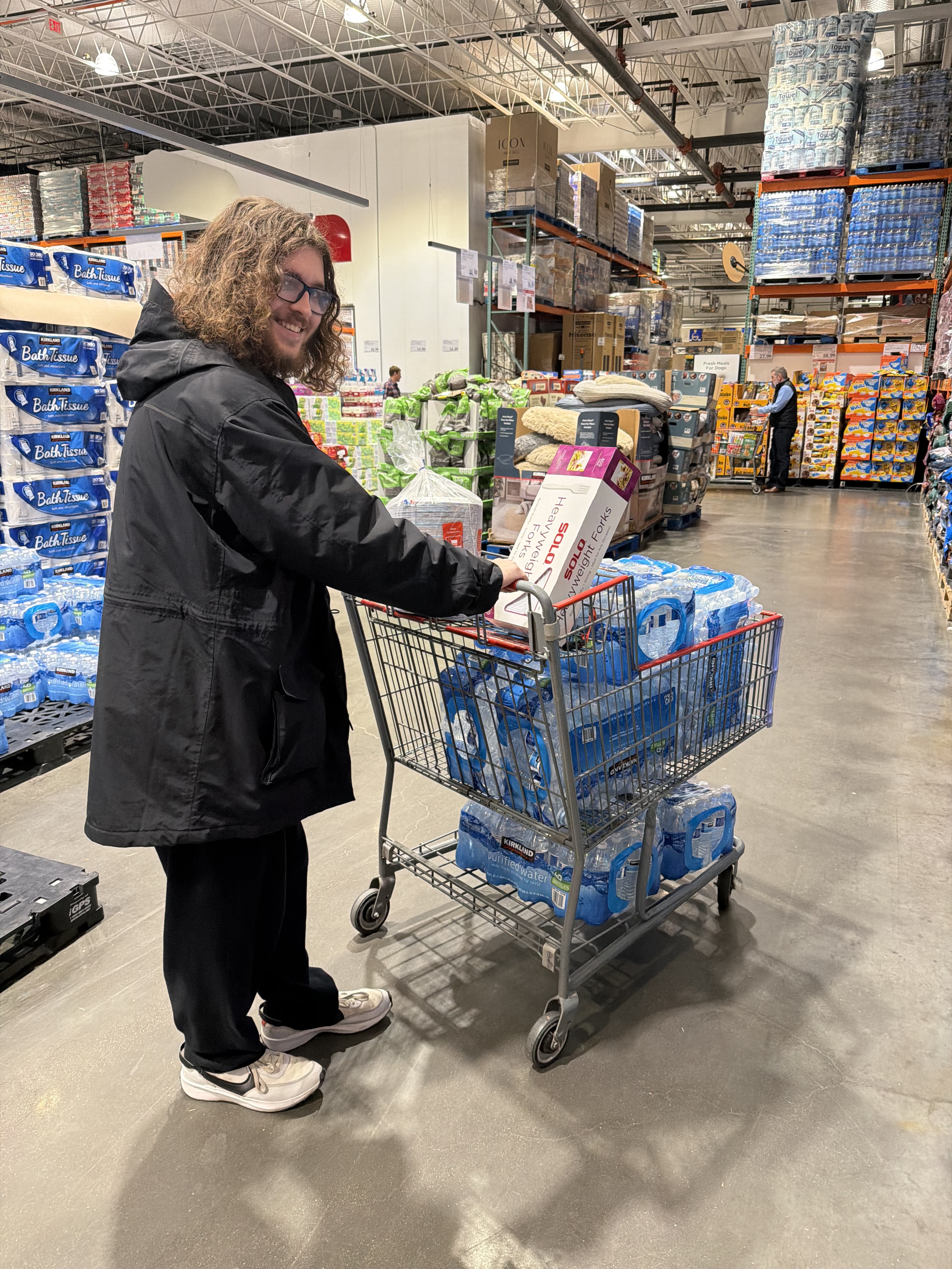Ben in Costco smiling next to a cart of water