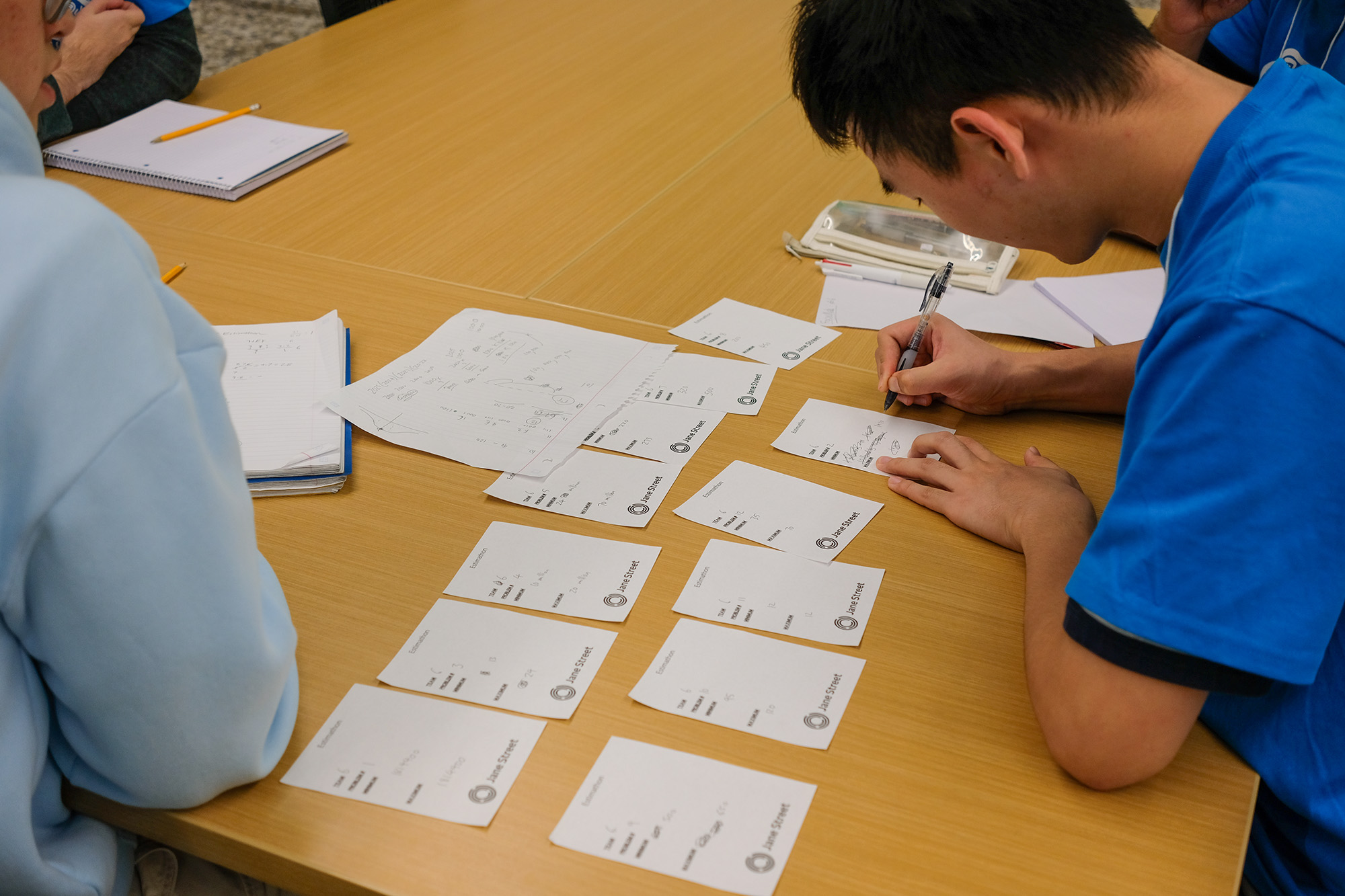 Estimathon participants writing their answers on Jane Street branded slips