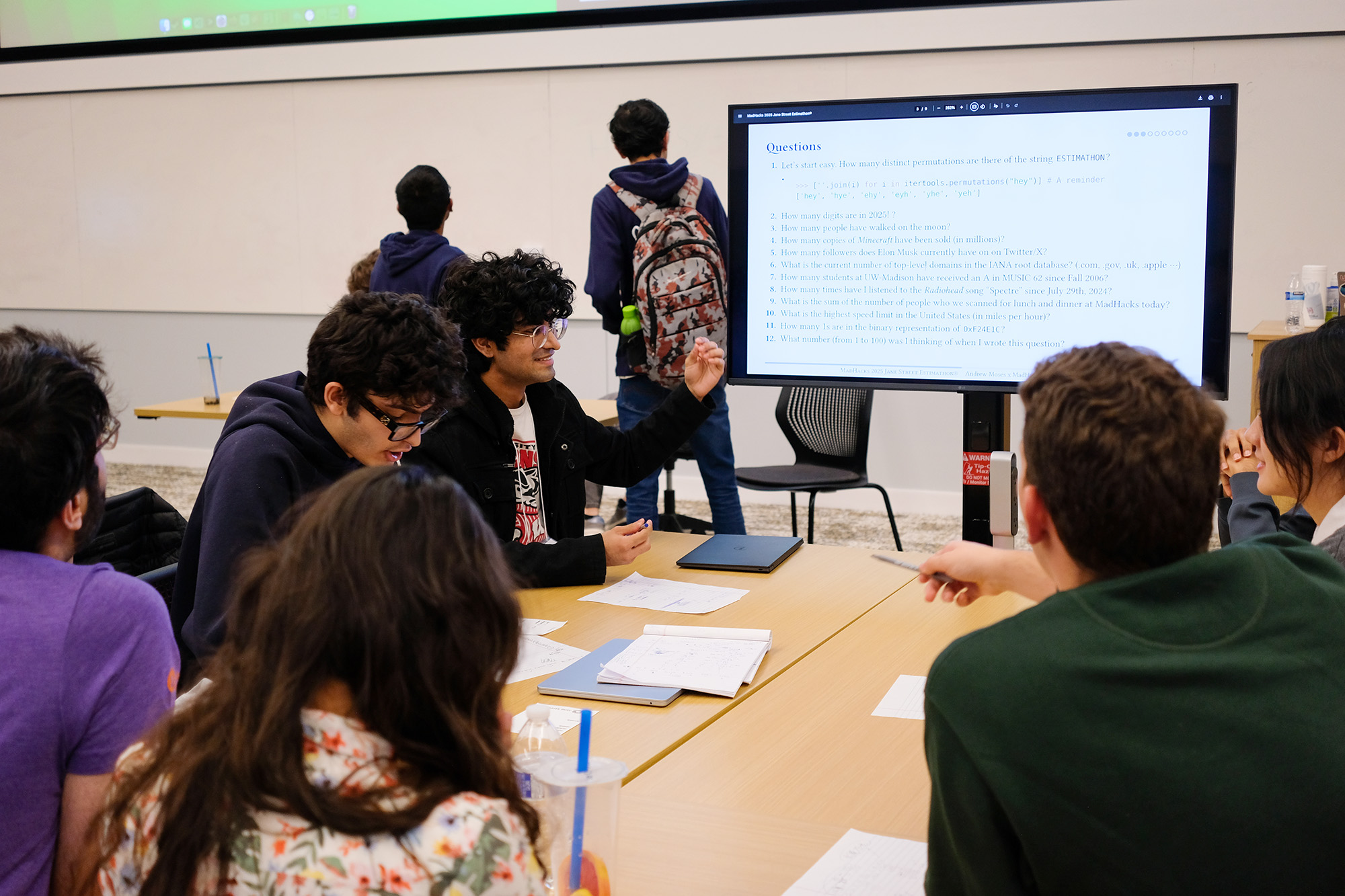 Estimathon participants discussing questions while looking at a monitor