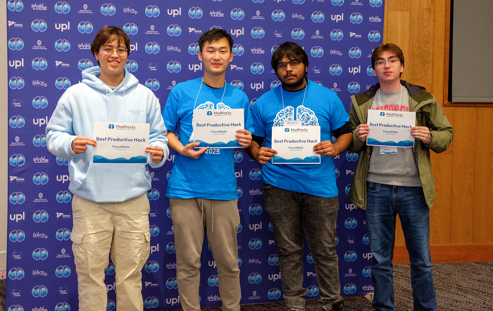 A MadHacks team poses with sheets that say 'Best Productive Hack'