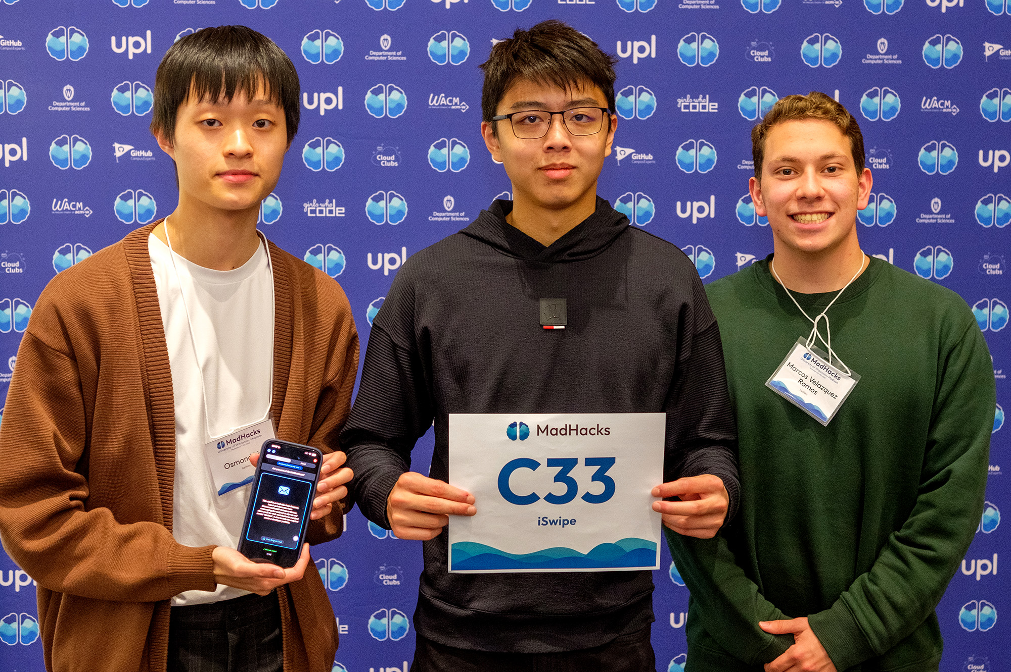 A MadHacks team poses with a sheet that says 'C33, iSwipe'